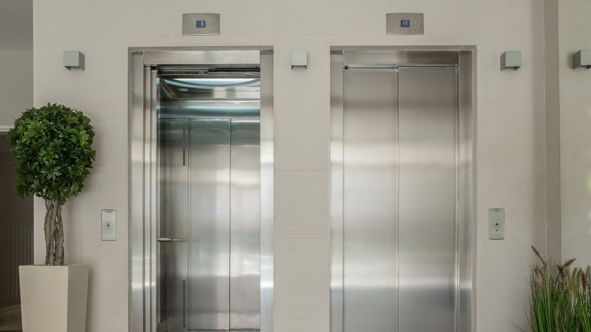 Modernos ascensores de acero inoxidable con servicio de reparación en el vestíbulo del edificio.